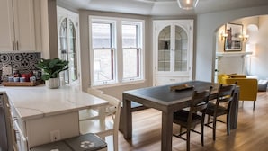 A modern kitchen with white cabinetry, a dining table, and a yellow chair.