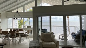 Un amplio salón con un ventanal que da a una terraza y al océano.