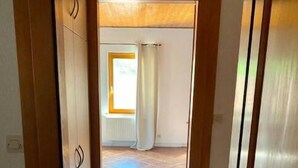 En hall med kakelgolv som leder till ett rum med ett fönster och gardiner.