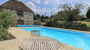 Ein Schwimmbecken mit einer Holzterrasse und einem Tisch.