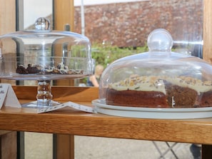 En dessertudstilling med to kager under glas Kuppeler på et træbord.