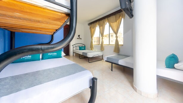 Habitación de hotel con literas, una cama individual, un escritorio y una ventana con cortinas.