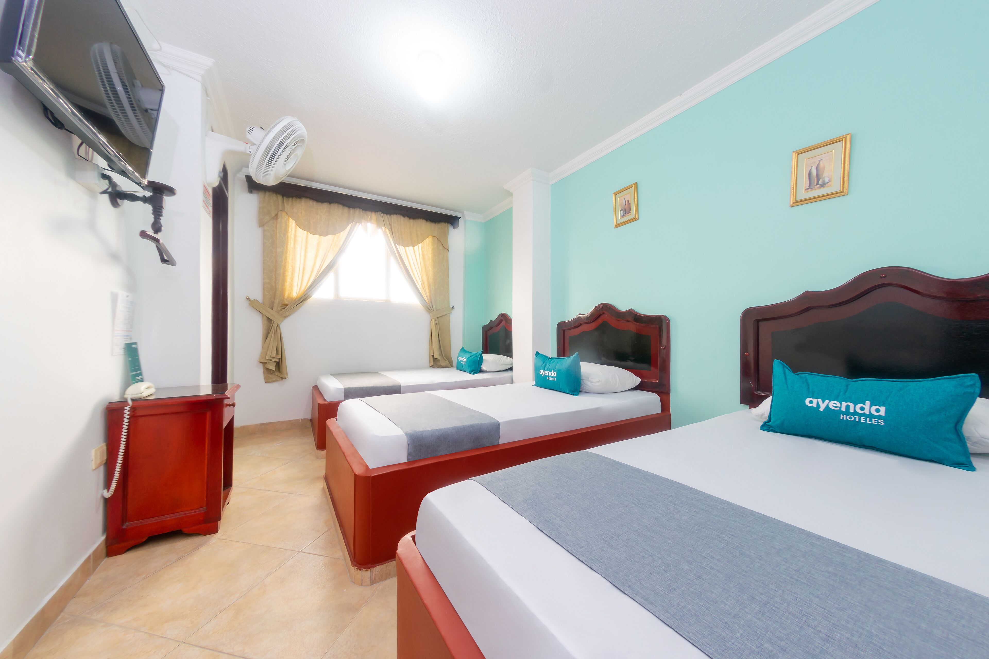 Habitación de hotel con dos camas, televisión, aire acondicionado y teléfono sobre una mesita de noche.
