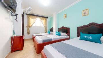 A hotel room with two beds, a TV, an air conditioner, and a telephone on a side table.