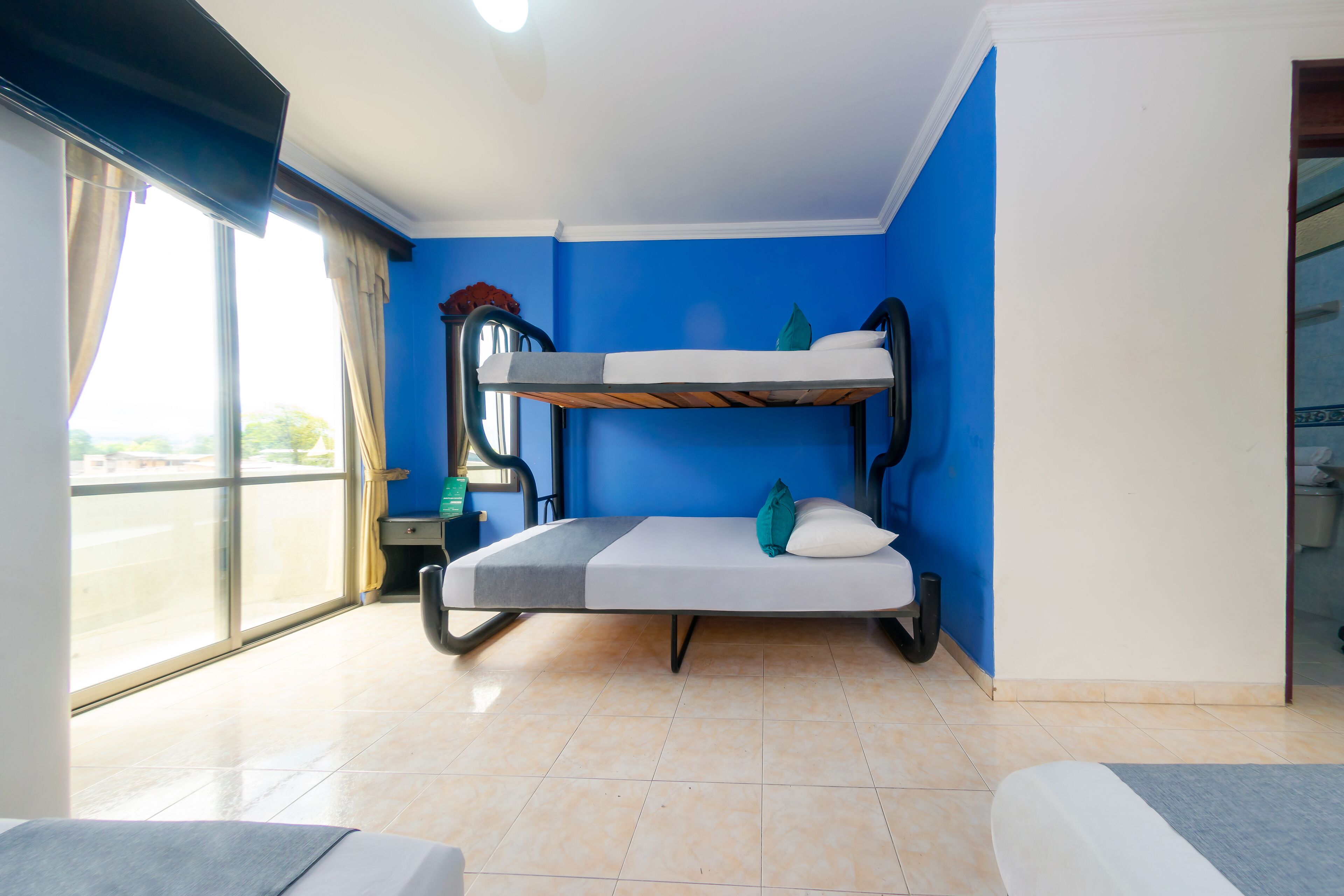 Habitación con literas, un sillón, una ventana grande y una mesita.