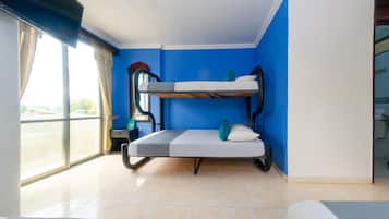 Habitación con literas, un sillón, una ventana grande y una mesita.