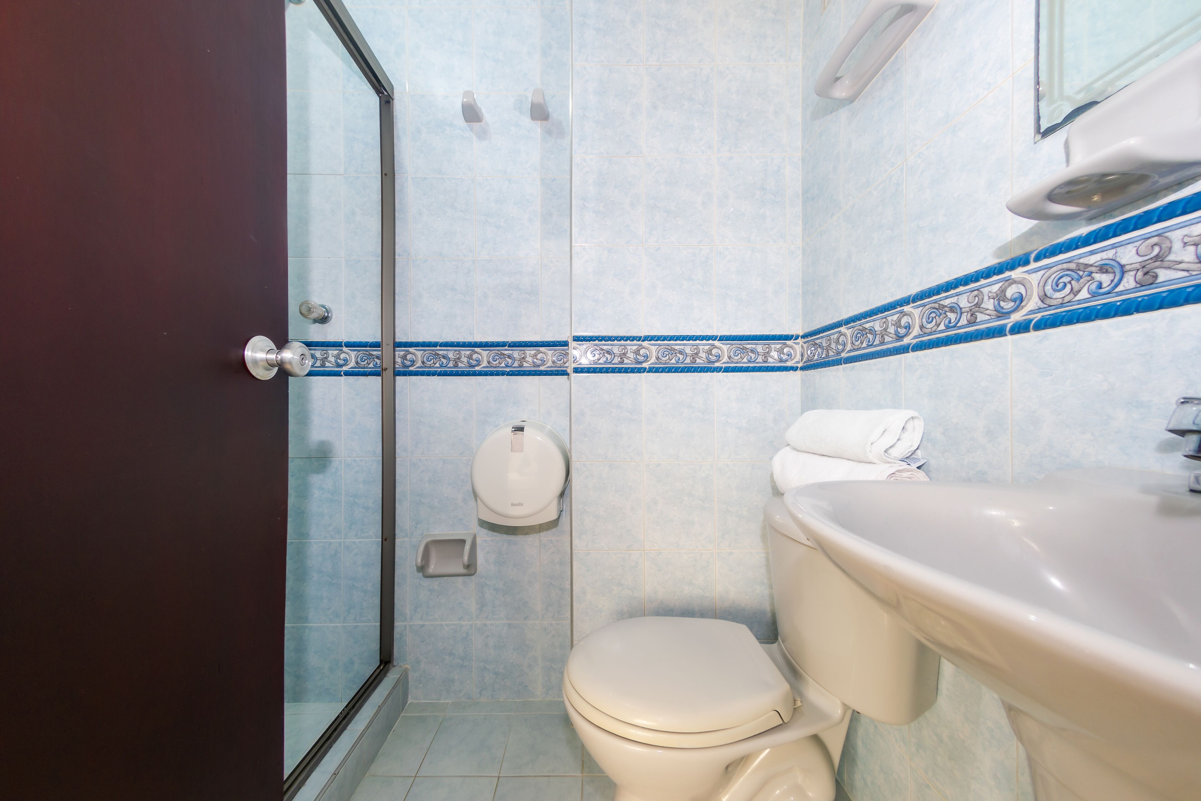 A bathroom with a toilet, sink, and a glass shower enclosure.