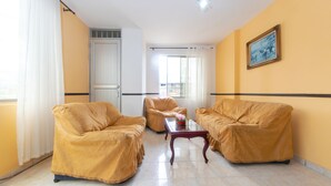 Una sala de estar con dos sofás tapizados, una mesa de centro y un ventanal con cortinas.