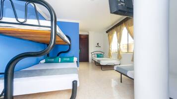 A room with a bunk bed, a sofa, a TV, and a window with curtains.