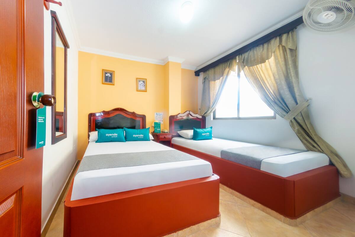 A hotel room with a large bed, a sofa bed, and a small table.