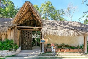 Une construction à toit de chaume, dotée d’une porte en bois et d’une enseigne.