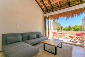 Un salon moderne avec un canapé, une table basse et une vue sur un balcon agrémenté de chaises rouges.