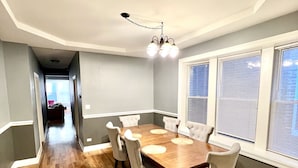 A dining area with a wooden table, six chairs, and a chandelier.