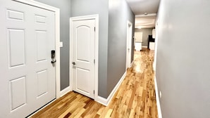 A hallway with wooden flooring, white doors, and grey walls.