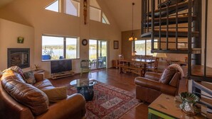 A spacious living room with a fireplace, leather sofas, a dining area, and a view of the outdoors.