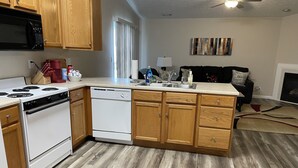 A modern kitchen with wooden cabinets, a white stove, and a dishwasher. - Colorful home near Purdue! (Lafayette)