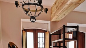 Una sala de estar acogedora con una puerta de madera, una estantería, un ordenador portátil sobre una mesa y una lámpara de pie.