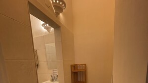 Un baño con lavamanos, espejo y estante de madera.