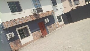A two-story house with a stone facade, a red door, and multiple windows. - Homewood Suites (Lekki)