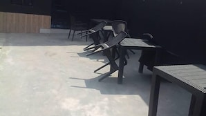 An outdoor patio area with several tables and chairs, a concrete floor, and a building in the background. - Homewood Suites (Lekki)
