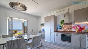 Eine moderne Küche mit Backofen, ein Essbereich mit gestreiften Stühlen und Blick ins Freie.
