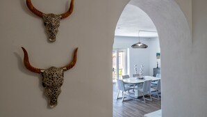 Ein modernes Interieur mit zwei dekorativen Stierhörnern an der Wand, das zu einem Essbereich mit Tisch und Stühlen führt.