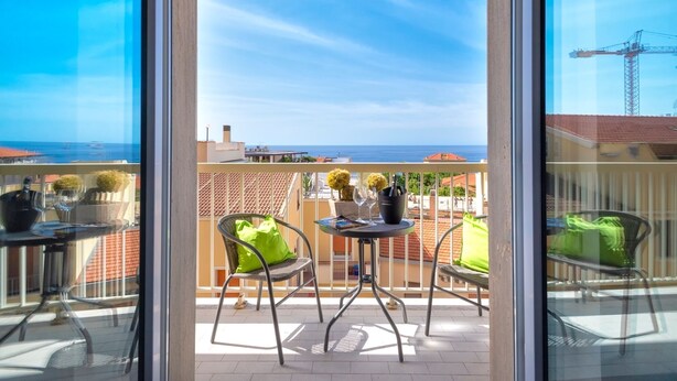 Ein Balkon mit Tisch, Stühlen und Meerblick.
