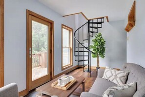 A modern living room with a curved staircase, a sofa, a coffee table, and a potted plant.