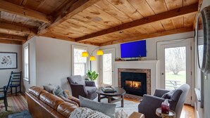 Una sala de estar acogedora con chimenea, sofá de cuero y televisor de pantalla plana montado arriba.