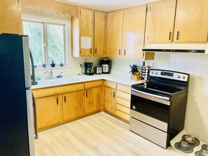 A kitchen with wooden cabinets, a stainless steel stove, a coffee maker, and a toaster.