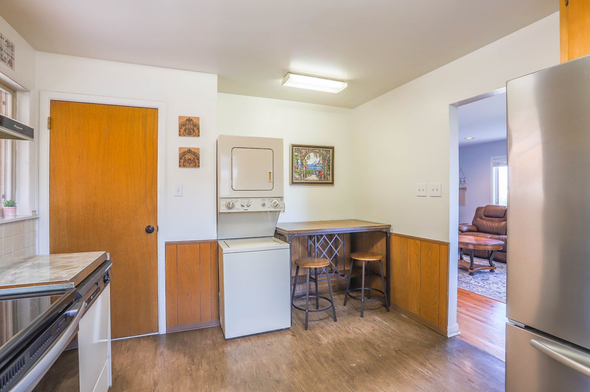 A compact kitchen with a stove, refrigerator, and a small dining area with stools.