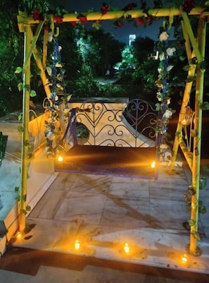 Un espace extérieur aménagé avec des sièges, agrémenté d’une rambarde en métal, de compositions florales et de bougies.