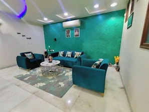 Un salon moderne avec des canapés de couleur turquoise, une table basse ronde et un mur d’accent vert.