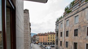 A balcony with a view of a city street, a building with a marble facade, and a bench. - Luxury Apartment With Balcony (Como)