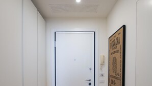 A hallway with a wooden floor, a white door, and a framed picture on the wall. - Luxury Apartment With Balcony (Como)