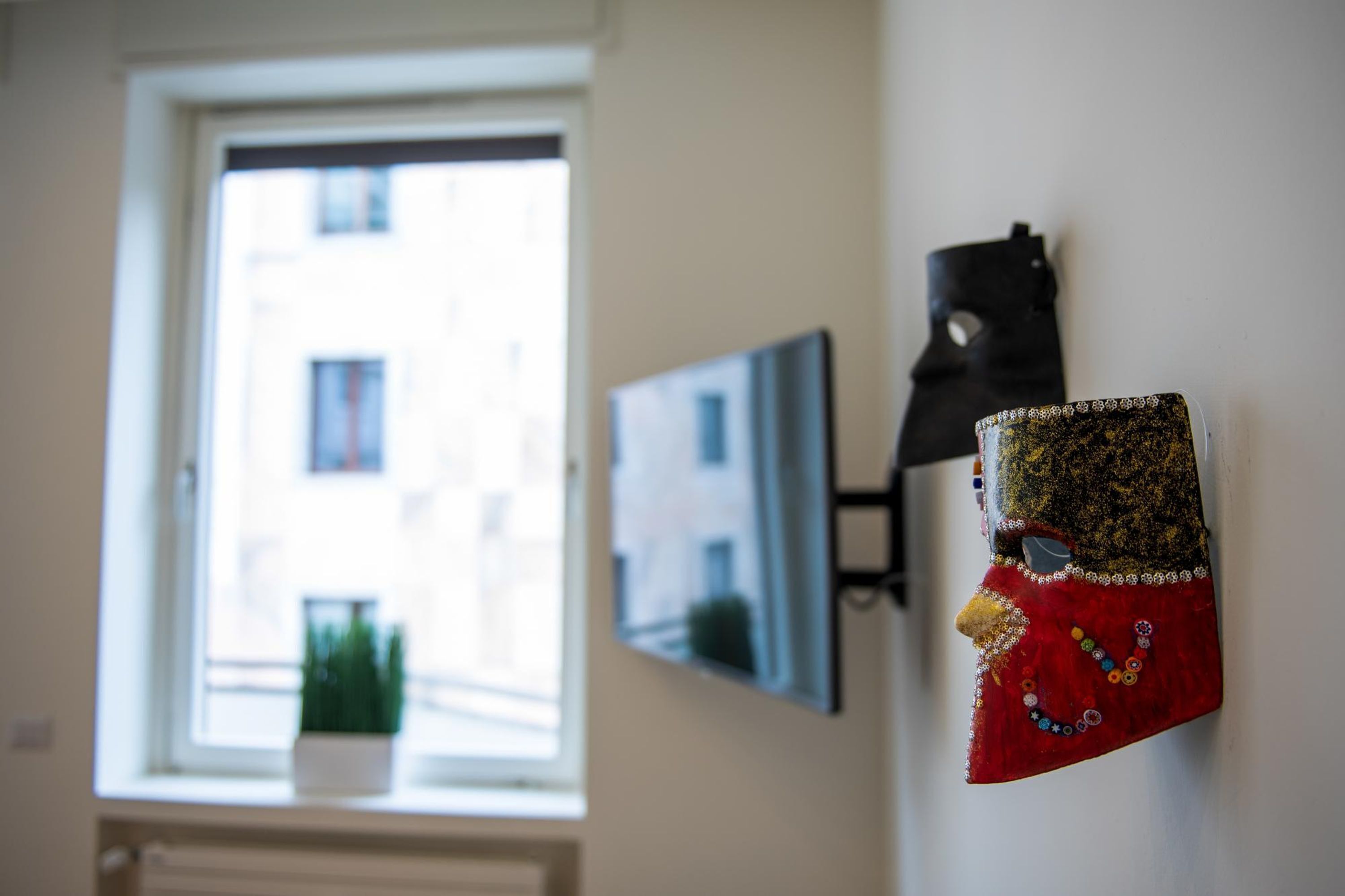 Une pièce avec une fenêtre, une lampe fixée au mur et un masque décoratif.