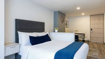 Une chambre d’hôtel moderne équipée d’un grand lit, d’une table de chevet, d’un bureau et d’une armoire.