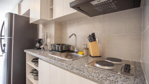 Una cocina moderna con refrigerador de acero inoxidable, cafetera integrada, pileta y cocina a gas.