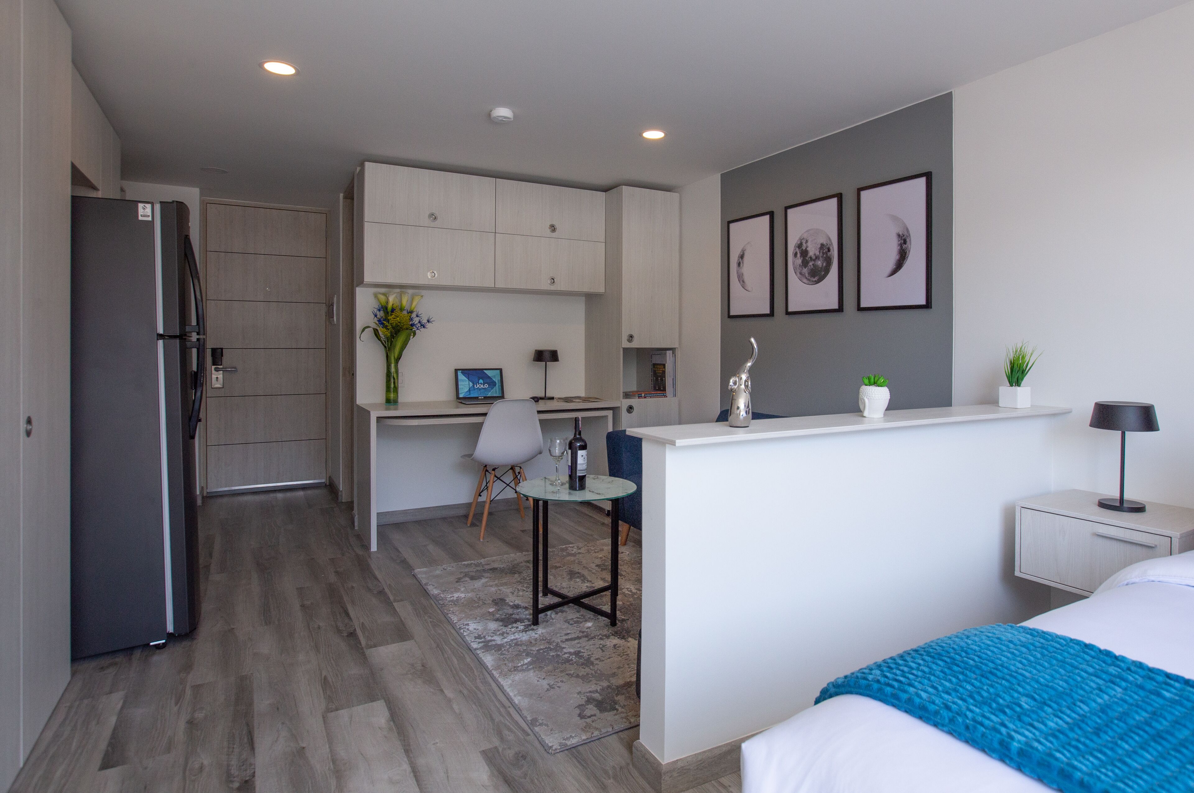 A compact hotel room with a kitchenette, a dining area, and a bed.