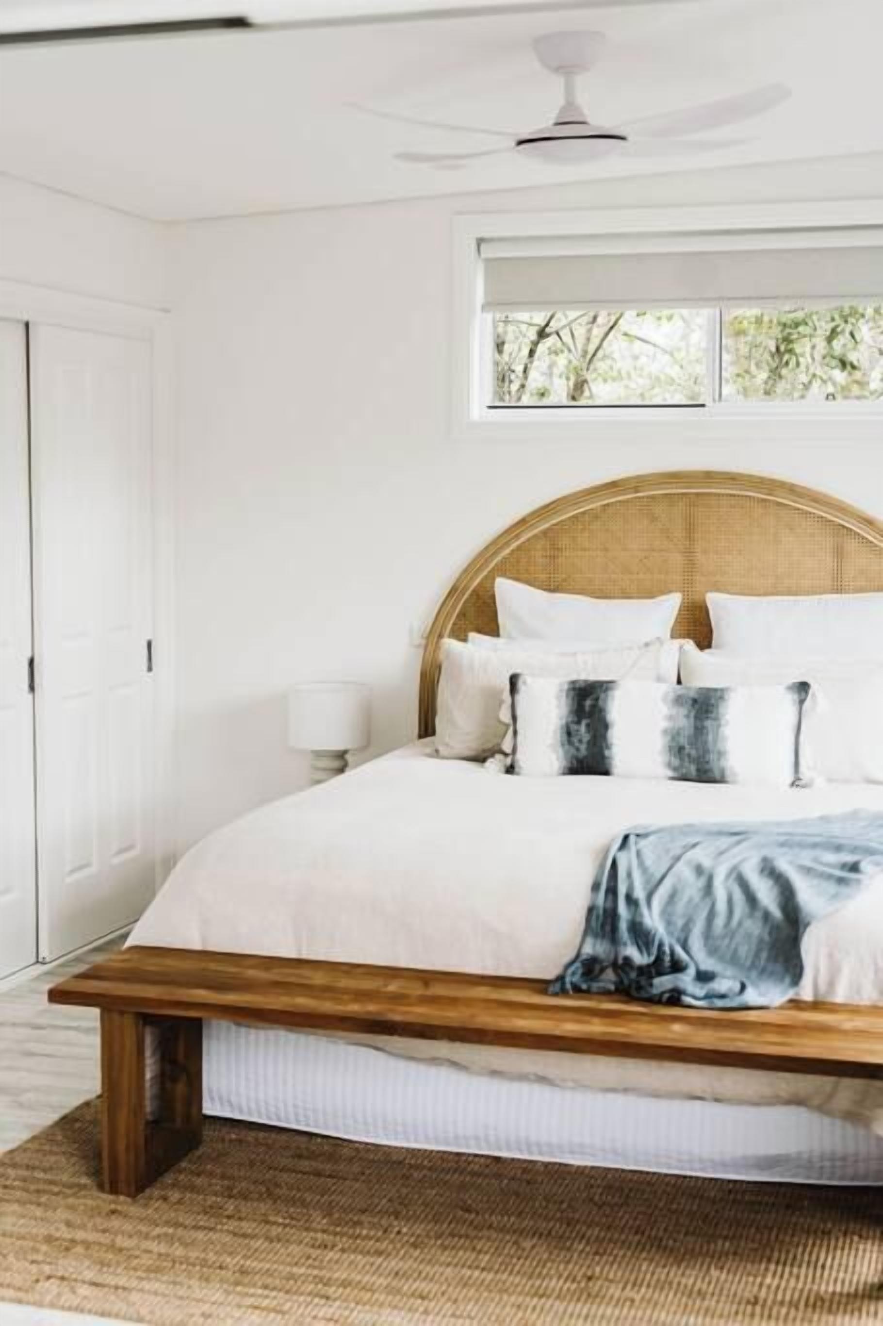 Un dormitorio con una cama, una mesita de noche, una lámpara y una ventana.