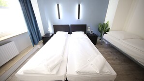 A double bed with white linens, a bedside table with a lamp, and a potted plant. - LUXOMES - Aparthotel Zentrum (Nuremberg)