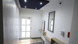 A hallway with a door, a mirror, a radiator, and a shelf with a framed picture. - LUXOMES - Aparthotel Zentrum (Nuremberg)