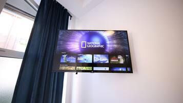 A flat-screen TV mounted on a wall displaying the National Geographic channel logo and various program thumbnails.