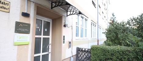 A building with a glass door entrance, a metal awning over the door, and signs for 'Luxomes' and 'Secco'.
