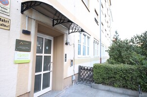 Un edificio con entrada de puerta de cristal, toldo metálico sobre la puerta y carteles que dicen 'Luxomes' y 'Secco'.