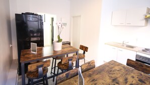 A compact kitchen with a wooden table and chairs, a black refrigerator, and white cabinets. - LUXOMES - Aparthotel Zentrum (Nuremberg)