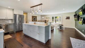 A modern kitchen with a central island, stainless steel appliances, and recessed lighting.