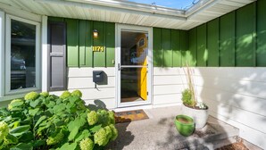 A house with a green exterior, a white door, and a mailbox.