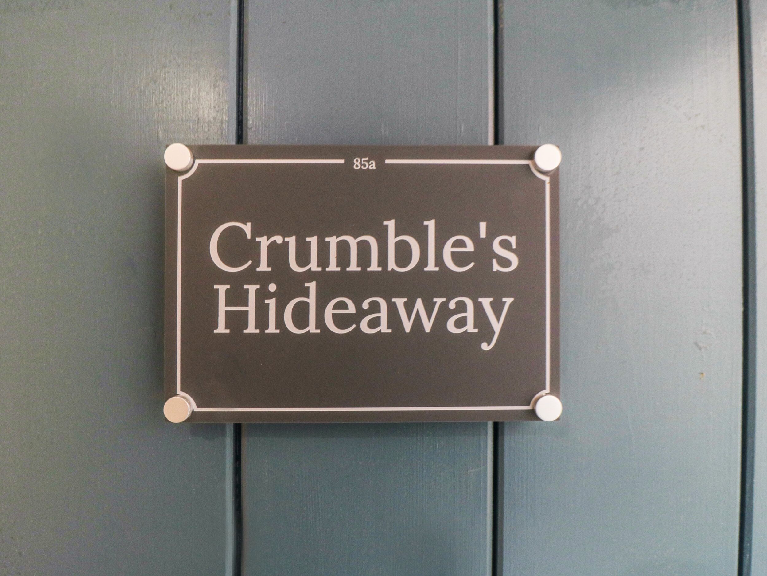 A sign reading "Crumble's Hideaway" mounted on a wall.