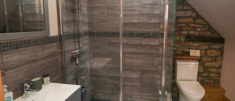Une salle de bain moderne avec une douche à parois de verre, des toilettes blanches et un meuble-lavabo avec un miroir et un évier.